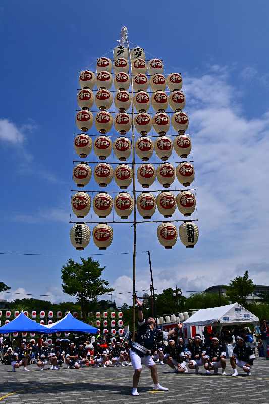 竿燈まつりの妙技大会の様子。男性が腰で竿燈を支えている写真。