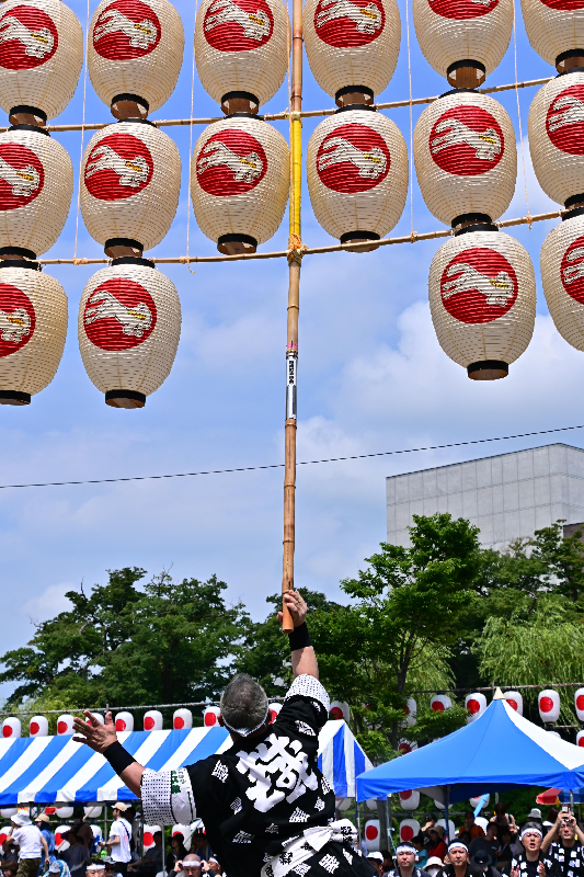 竿燈まつりの妙技大会の様子。男性が肩に竿燈を載せようとしている画像。