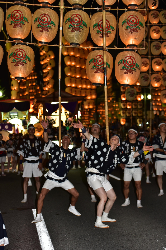 男性が二人並んで竿燈を上げている画像