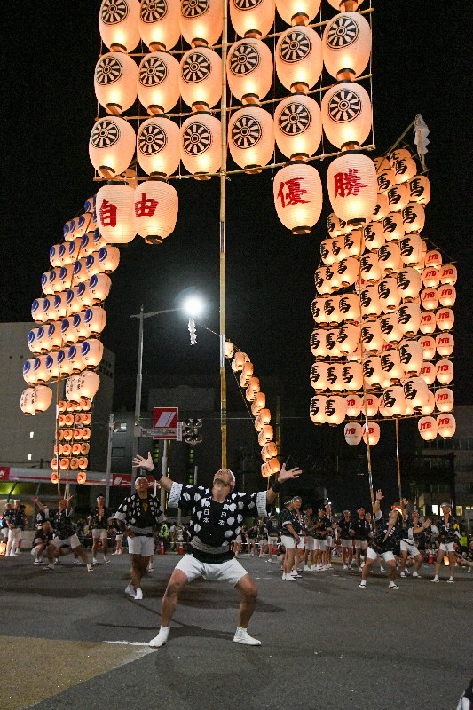 額で竿燈を上げている男性の写真。背後に５本の竿燈が上がっている。