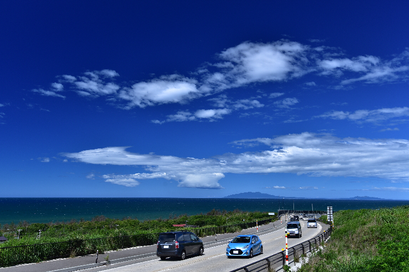青空と海の近くの道路を写した画像